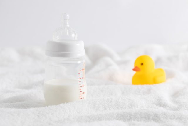 closeup bottle full milk duck toy white surface
