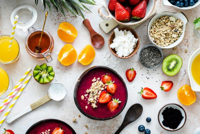 preparing acai bowl flat lay style with tropical fruits grains