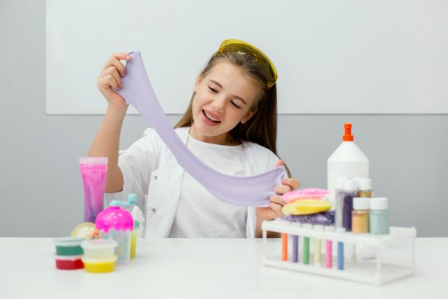 smiley young girl scientist making slime