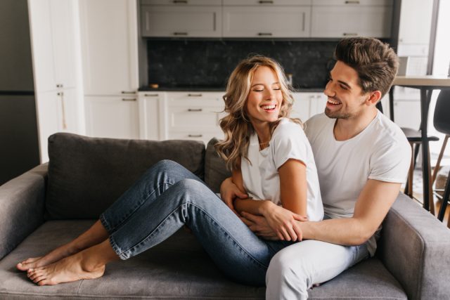 joyful day together cozy warm apartments happy attractive guy with beautiful girl looking each other laughing hugging sofa
